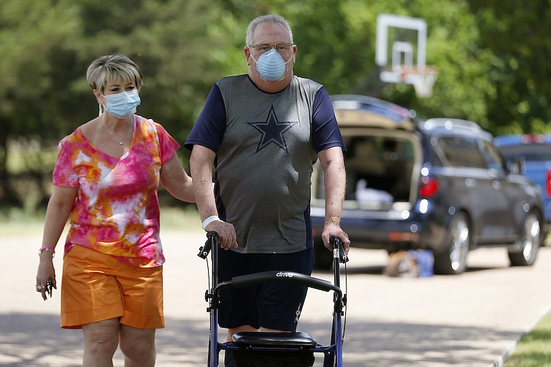 Terri Donelson, left, and her husband, Stephen, walk up their driveway to see friends and family awaiting him at his home in Midlothian, Texas on Friday, June 19, 2020, after his 90-day stay in the Zale Hospital on the UT Southwestern Campus. Donelson's family hadn't left the house in two weeks after COVID-19 started spreading in Texas, hoping to shield the organ transplant recipient. Yet one night, his wife found him barely breathing, his skin turning blue, and called 911. (AP Photo/Tony Gutierrez)