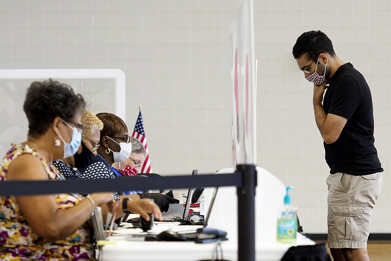Staff photo by C.B. Schmelter / Shazman Ali, right, checks in to vote at the Brainerd Youth and Family Development Center on Saturday, Aug. 1, 2020 in Chattanooga, Tenn. Saturday marked the end of the early voting period.
