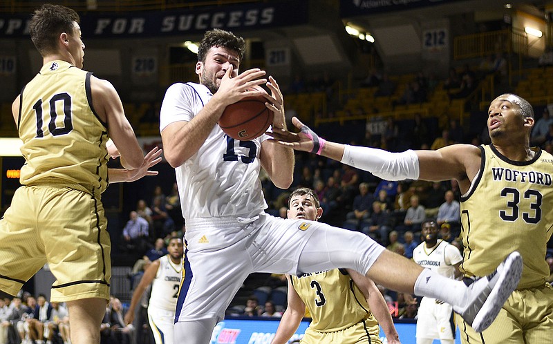 Staff photo by Robin Rudd / UTC'S Ramon Vila, center, wins an offensive rebound in between Wofford's Nathan Hoover (10) and Cameron Jackson during a SoCon game on Feb. 28, 2019, at McKenzie Arena.