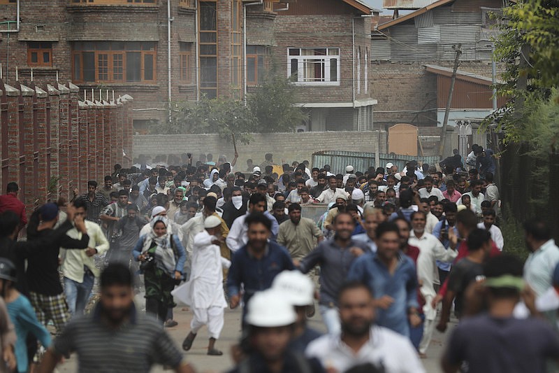 In this Aug. 30, 2019, file photo, Kashmiris protesting against Indian government stripping the Himalayan state's semi-autonomous powers run for cover as Indian police use tear gas and pellets to disperse them in Srinagar, Indian controlled Kashmir. A year after India ended disputed Kashmir's semi-autonomous status and downgraded it to a federally governed territory, authorities have begun issuing residency and land ownership rights to outsiders for the first time in almost a century. Many Kashmiris view the move as the beginning of settler colonialism aimed at engineering a demographic change in India's only Muslim-majority region. (AP Photo/Mukhtar Khan, File)