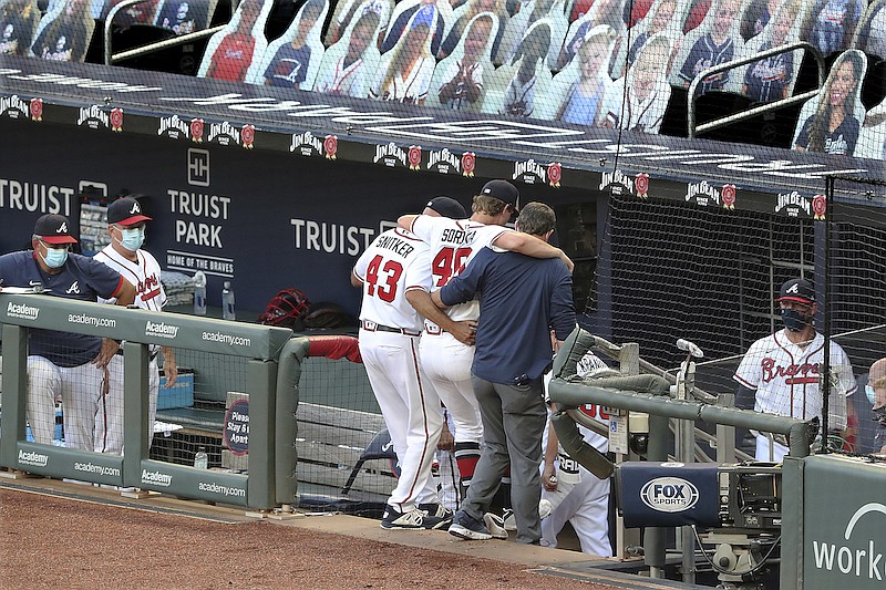AP photo by Curtis Compton / Atlanta Braves manager Brian Snitker, left, and a trainer help pitcher Mike Soroka off the field after he tore an Achilles' tendon during Monday night's home game against the New York Mets.
