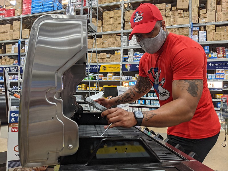 Photography by Michelle Michaud / Assemblers Incorporated employee Brandon Elder assembles a grill at the Lowe's store on Gunbarrel Road.