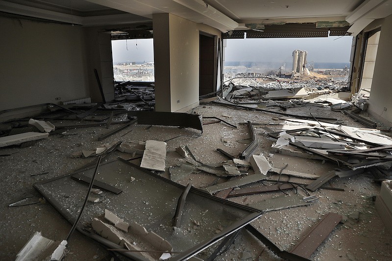 The scene of the explosion that hit the seaport of Beirut is seen through a damaged apartment in Beirut, Lebanon, Wednesday, Aug. 5, 2020. Prime Minister Hassan Diab, in a short televised speech, has appealed to all countries and friends of Lebanon to extend help to the small nation, saying: "We are witnessing a real catastrophe." (AP Photo/Hussein Malla)