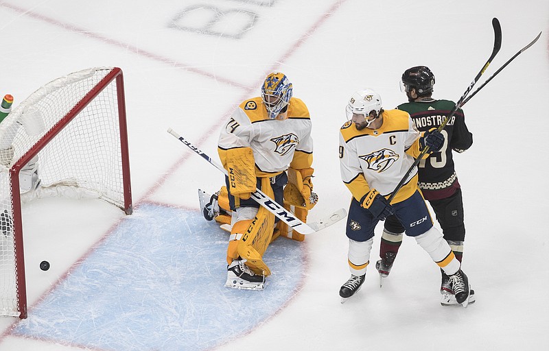 AP photo by Jason Franson / The puck goes past goalie Juuse Saros and into Nashville's net as the Arizona Coyotes' Brad Richardson, right, battles with the Predators' Filip Forsberg during the first period of Friday's game in Edmonton. Arizona won 4-3 in overtime to take the best-of-five NHL qualifying series in four games.