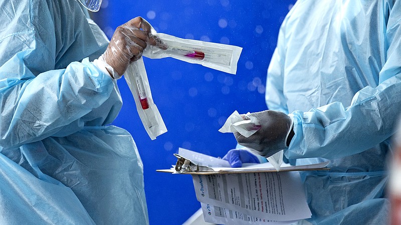In this July 23, 2020 file photo, health care workers prepare a COVID-19 test sample before a person self-administered a test at the COVID-19 drive-thru testing center at Miami-Dade County Auditorium in Miami. Racial disparities in the the U.S. coronavirus epidemic extend to children, according to two sobering government reports released Friday, Aug. 7. One of the Centers for Disease Control and Prevention reports looked at hospitalizations of children with COVID-19. Hispanic children were hospitalized at a rate eight times higher than white kids, and Black children were hospitalized at a rate five times higher, it found.(David Santiago/Miami Herald via AP)