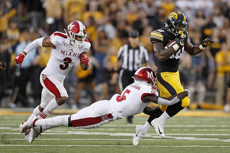 AP photo by Charlie Neibergall / Iowa running back Mekhi Sargent tries to break a tackle by Miami (Ohio) defensive back Emmanuel Rugamba on Aug. 31, 2019, in Iowa City. Both the Big Ten Conference, which Iowa is a member of, and the Mid-American Conference, to which Miami belongs, made announcements Saturday that could be considered ominous for the prospect of any college football being played this fall.