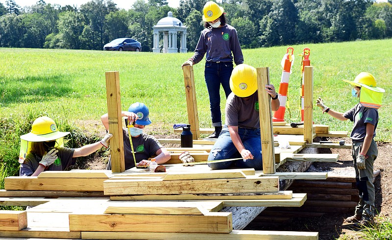 Staff Photo by Robin Rudd / From left, Southeast Conservation Crops team members Juliana Willams, Emily Mathis, Autumn Beeland, Ruth Beeland and Gracie Fogo build a footbridge being build across a stream, in the McDonald Field, just south of the Chickamauga National Military Park's visitor center on Wednesday.