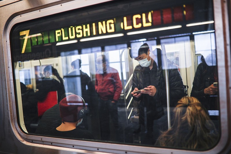 FILE - In this April 7, 2020, file photo, some people wear masks while using the New York City subway system during the coronavirus pandemic in New York. New York's mass transit agency wants Apple to come up with a better way for iPhone users to unlock their phones without taking off their masks, as it seeks to guard against the spread of COVID-19 in buses and subways. (AP Photo/John Minchillo, File)