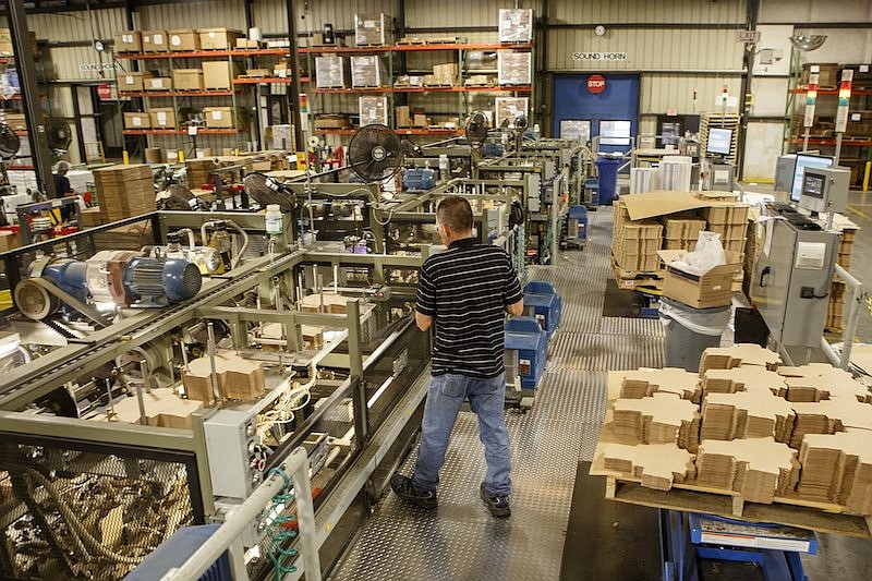 Staff file photo by C.B. Schmelter / An employee works on loading unfolded boxes into a machine at Southern Champion Tray at the company's Compress Street location in 2019.