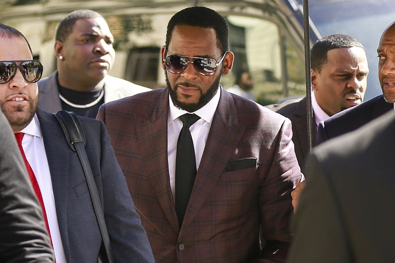 In this June 26, 2019 file photo, R&B singer R. Kelly, center, arrives at the Leighton Criminal Court building for an arraignment on sex-related felonies in Chicago. Federal prosecutors announced charges Wednesday, Aug. 12, 2020, against three men accused of threatening and intimidating women who have accused Kelly of abuse, including one man suspected of setting fire to a vehicle in Florida. (AP Photo/Amr Alfiky, File)