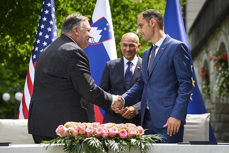 US Secretary of State Mike Pompeo, left, and Slovenia's Foreign Minister Anze Logar shake hands after signing an agreement on fifth-generation internet technology as Slovenia's Prime Minister Janez Jansa stands at center, in Bled, Slovenia, Thursday, Aug. 13, 2020. Pompeo is on a five-day visit to central Europe with a hefty agenda including China's role in 5G network construction. (Jure Makovec/Pool Photo via AP)