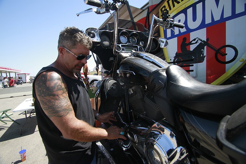 Chris Cox, the founder of Bikers for Trump, examines his motorcycle on Saturday, Aug. 8, 2020, outside the Bikers for Trump trailer he brought to the Sturgis Motorcycle Rally, in Sturgis, S.D. The group has taken advantage of recent motorcycle rallies, which have been some of the largest mass gatherings in the country, to make direct appeals to register to vote. While the group has gained a significant online following for its shows of bravado, it remains to be seen if they can get ballot boxes filled with bikers, many who hail from the suburbs. (AP Photo/Stephen Groves)