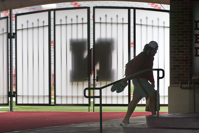 AP photo by Nati Harink / A football player carries his shoes and a lunch bag in front of a closed gate leading to the University of Nebraska's playing field at Memorial Stadium on Wednesday in Lincoln, Neb. Nebraska is part of the Big Ten, which is one of the conferences that has postponed its traditional fall sports calendar to the spring semester.