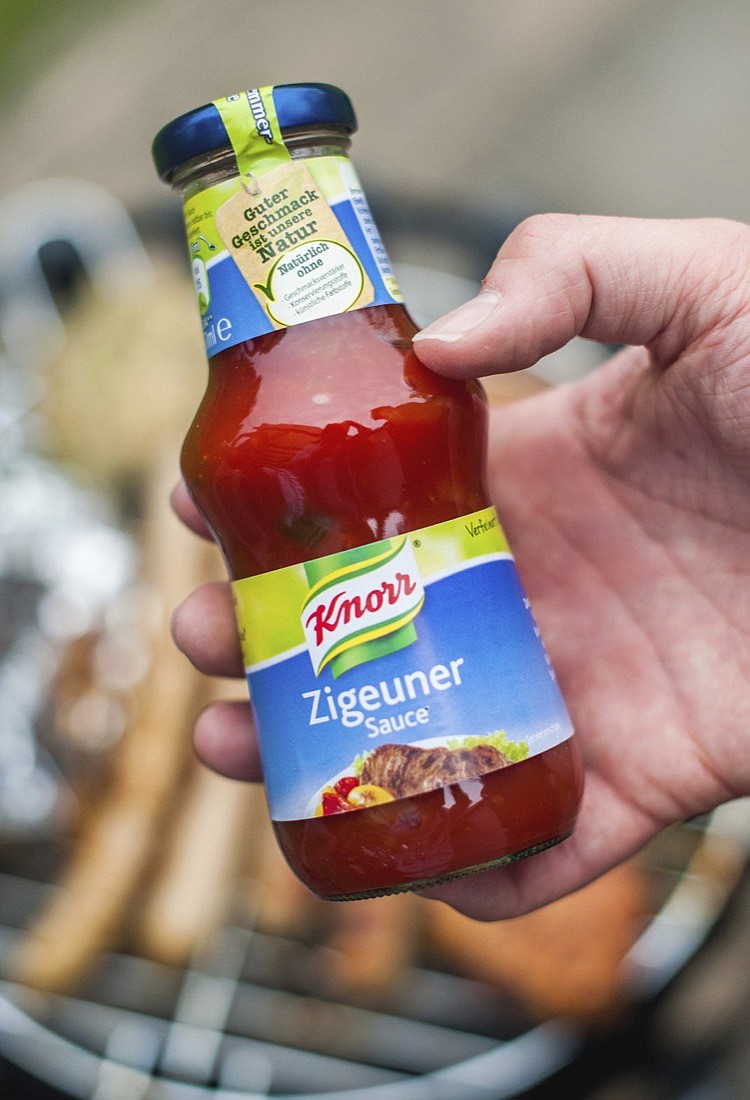 FILE- In this May 6, 2014 taken photo a man holds a bottle of "gypsy sauce" from the manufacturer Knorr in his hand in Berlin, Germany. One of Germany's best-known food brands has renamed a popular spicy dressing because of the racist connotations of the name. Knorr will change the name of its "Zigeuersauce," or "gypsy sauce" to Paprika Sauce Hungarian Style," German weekly Bild am Sonntag reported on Sunday. (Hauke-Christian Dittrich/dpa via AP)