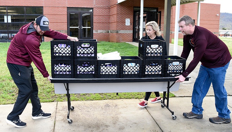 Staff Photo by Robin Rudd / From left, Justin Page, Dade Elementary PE teacher, Tracy Blevins, Dade Elementary principal, and Dade Middle School assistant principal Heath Johnson move crates of milk to the buses.