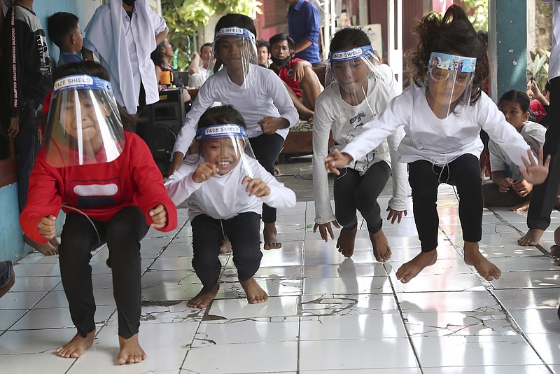 Children wearing masks as a precaution against the coronavirus, take part in a "leap frog" race during a performance held as a part of a celebration of the country's 75th anniversary of independence in Tangerang, Indonesia, Monday, Aug. 17, 2020. (AP Photo/Tatan Syuflana)