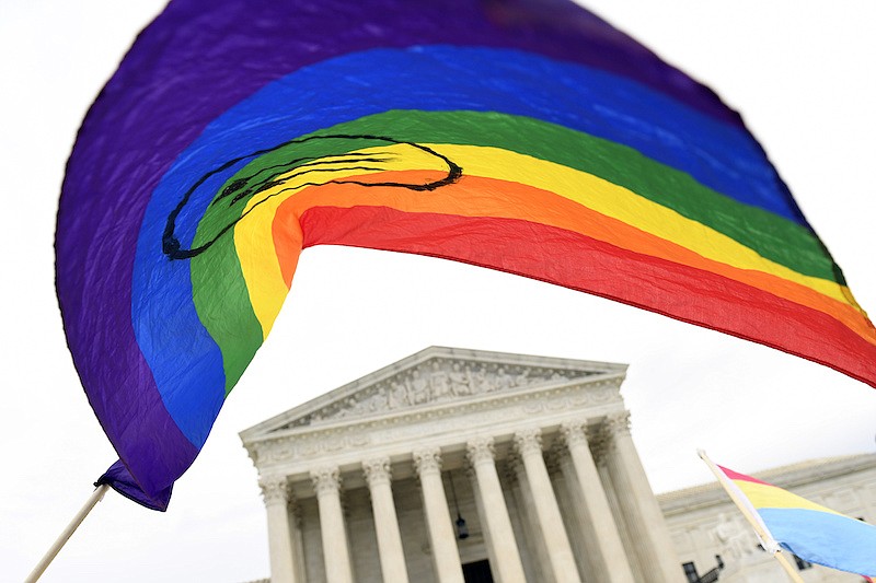 In this Oct. 8, 2019, file photo, people gather outside the Supreme Court in Washington. A federal judge has blocked the Trump administration from enforcing a new regulation that would roll back health care protections for transgender people. The regulation from the federal Department of Health and Human Services was finalized days after the Supreme Court barred sex discrimination against LGBT individuals on the job. (AP Photo/Susan Walsh, File)