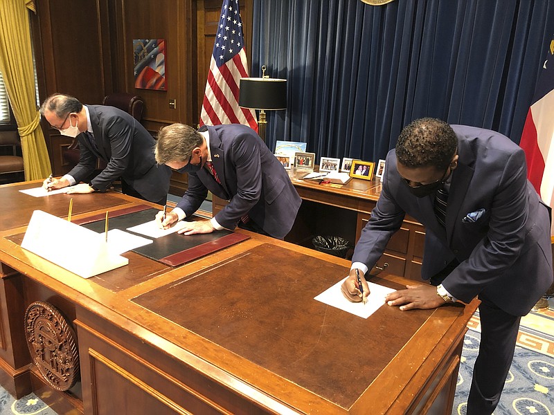 Zinus USA President Ha Bong Sung, Georgia Gov. Brian Kemp and Henry County Development Authority Chairman Pierre Clements sign papers on Tuesday, August 18, 2020 at the state Capitol in Atlanta. Zinus, a South Korean mattress and furniture maker, plans to build a $108 million factory and distribution center in McDonough, south of Atlanta. (AP Photo/Jeff Amy)


