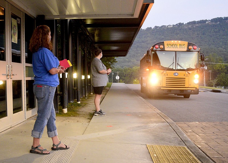 Staff Photo by Robin Rudd / From left, Special Education teacher Erin Knight and Girl's Physical Education teacher Deanna Wilson await the arrival of bus at the north entrance of Red Bank Middle School. Students arrived in significantly reduced numbers at Red Bank Middle School before 7:00 a.m. on Aug. 12, 2020.