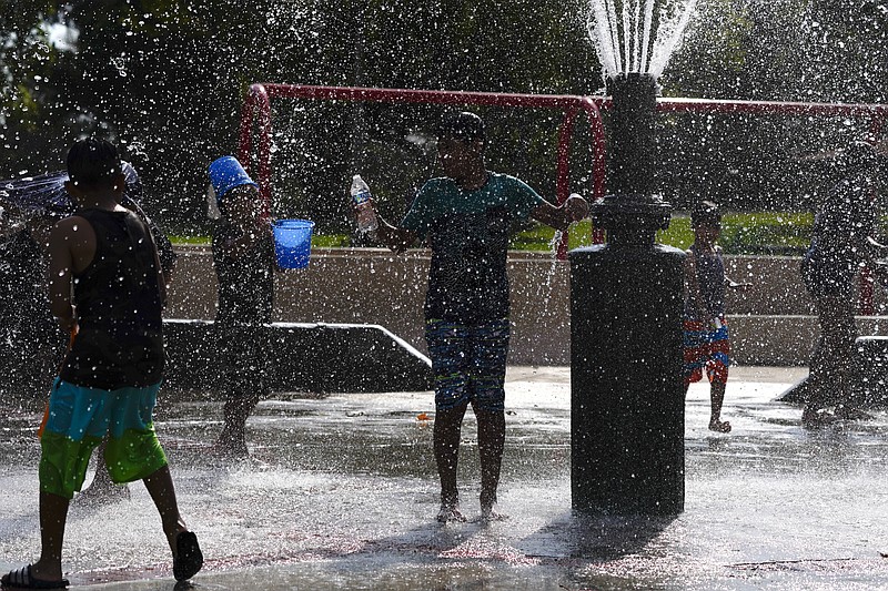 Children cool off in a park Tuesday, Aug. 18, 2020, in Fountain Valley, Calif. The state is in a days-long heat wave that has stressed the electrical system and resulted in rolling blackouts over two nights last weekend. (AP Photo/Jae C. Hong)