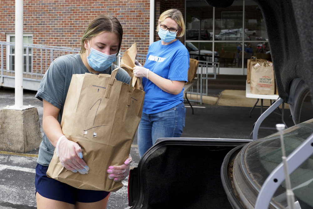 Staff photo by C.B. Schmelter / Sasha Murphy, left, and Nicky Murphy load bags of food from the Red Bank Community Food Pantry into a trunk at Red Bank United Methodist Church on Thursday, Aug. 20, 2020 in Chattanooga, Tenn.