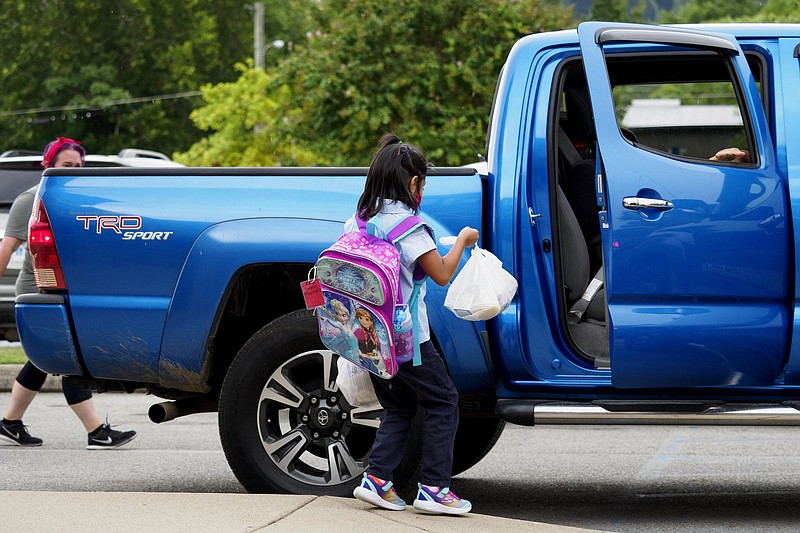 Staff photo by C.B. Schmelter / Teresa Maricela Ramos Miranda carries her meals to her car at East Side Elementary on Friday, Aug. 21, 2020 in Chattanooga, Tenn.