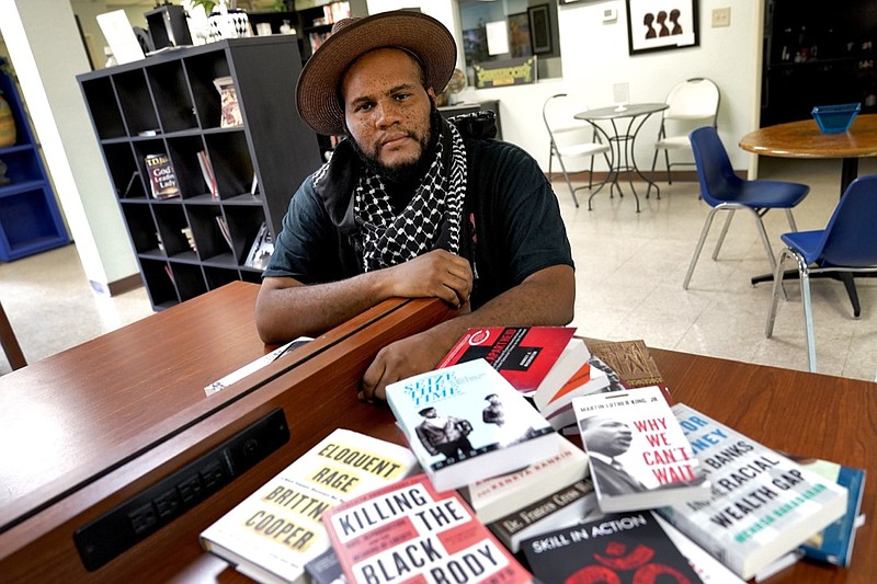 Owner Ali Nervis displays books on race relations at his bookstore Friday, Aug. 21, 2020 in Phoenix. Black-owned bookstores across the U.S. have seen increased sales following the police killings of Breonna Taylor and George Floyd, and store owners are now asking people who have read about Black history and culture to take action against the systems that have enabled racism. (AP Photo/Matt York)