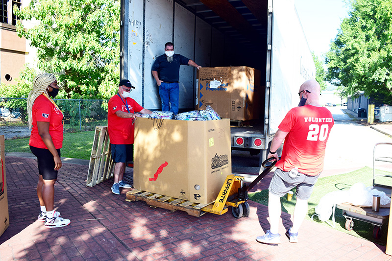 Staff Photo by Robin Rudd / Volunteers unload a truck of school supplies.