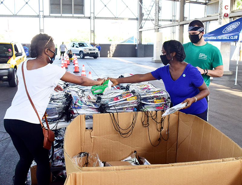 Staff Photo by Robin Rudd / As cars begin to enter the pavilion, Angela Clark, center, gives out gloves to Yvette Stewart and Brody Scott.