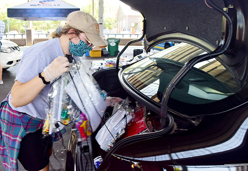 Staff Photo by Robin Rudd / Rachel Emond fills a family's trunk with supplies. Families were encouraged to open their trunks to lessen exposure for themselves and volunteers.