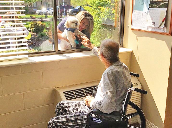 Contributed photo / A volunteer and her dog greet a resident at NHC HealthCare.