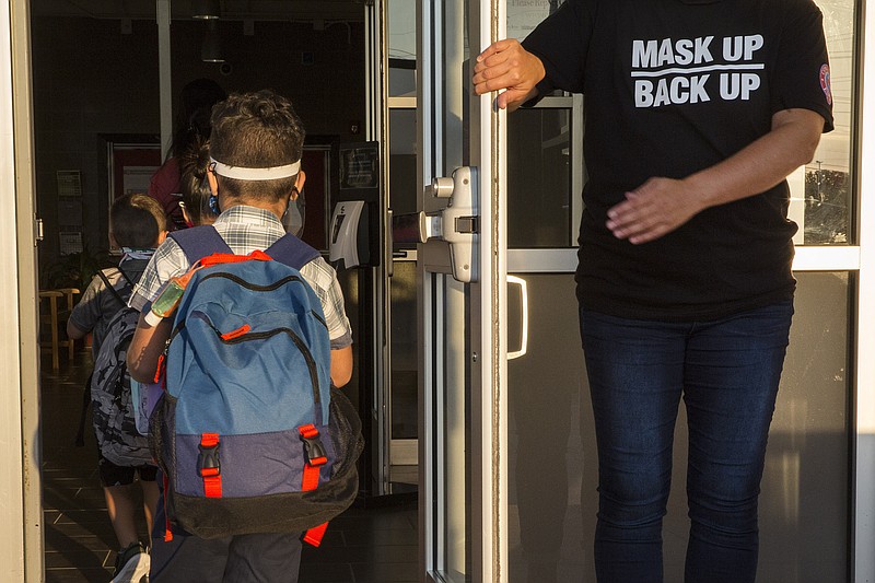 A staff member holds the door open for kids on the first day of school at Goodwin Frazier Elementary School in New Braunfels, Texas on Tuesday, Aug. 25, 2020. The number of Americans newly diagnosed with the coronavirus is falling — a development experts credit at least partly to increased wearing of masks — even as the outbreak continues to claim nearly 1,000 lives in the U.S. each day. (Mikala Compton/Herald-Zeitung via AP)


