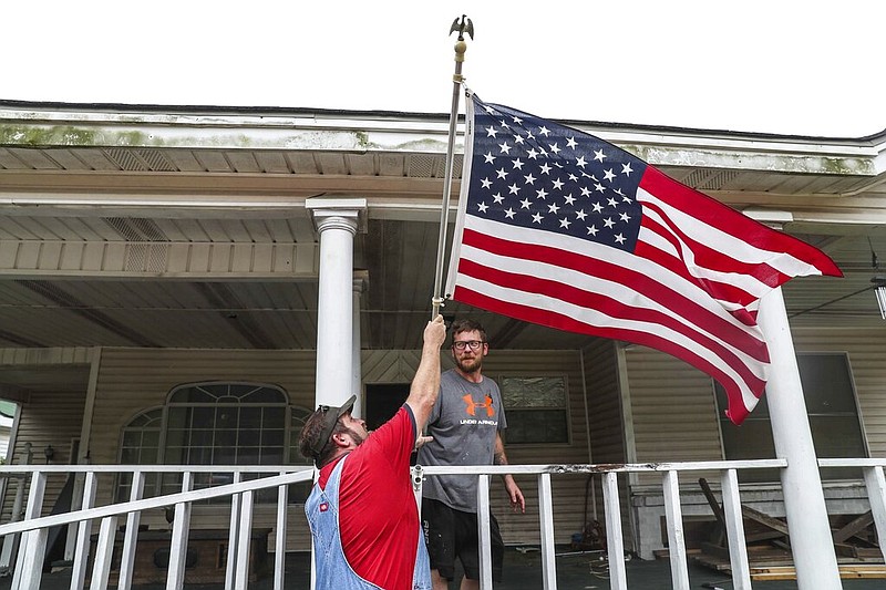 Bob Keen and Jonathan Trotti take down the American flag from their front porch to keep it safe inside the house while they prepare to evacuate the area as Hurricane Laura approaches in West Orange on Wednesday, August 26, 2020. (Lola Gomez/Austin American-Statesman via AP)