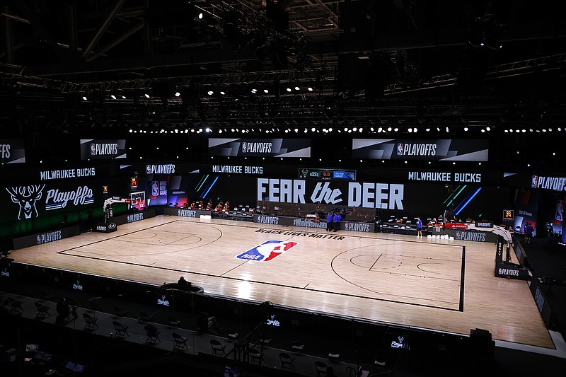 AP photo by Kevin C. Cox / NBA referees huddle on an empty court at game time of a scheduled playoff matchup between the Milwaukee Bucks and the Orlando Magic on Wednesday in Lake Buena Vista, Fla.