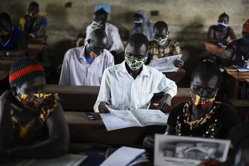 A trainee reads a handbook on coronavirus prevention, at a training session for community health workers conducted by the national NGO "Health Link" in Gumbo, on the outskirts of Juba, South Sudan, Tuesday, Aug. 18, 2020. The coronavirus is exposing an uncomfortable inequality in the billion-dollar system that delivers life-saving aid to countries in crisis: Most money goes to international aid groups instead of local ones and now many local aid workers have been left exposed on the pandemic's front lines. (AP Photo/Charles Atiki Lomodong)