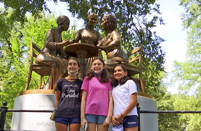 Jaya Shri, 13, , right stands with friends at the unveiling of a new statue honoring suffragettes in Central Park on Wednesday, Aug. 26, 2020. bronze statue depicting women's rights pioneers Sojourner Truth, Elizabeth Cady Stanton and Susan B. Anthony was unveiled in Central Park on Wednesday. It's the 167-year-old park's first monument honoring real historical women — as opposed to fictional heroines like Alice in Wonderland and Shakespeare's Juliet. (AP Photo/Ted Shaffrey)