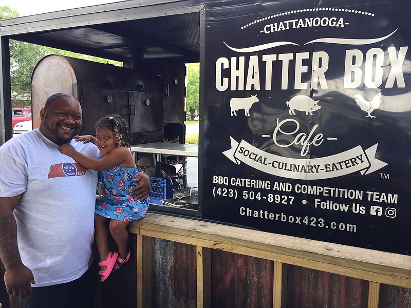 Brandon Ellis and his 2-year-old daughter, Harper, are pictured by Ellis' Chatter Box barbecue truck. / Staff Photo by Mark Kennedy