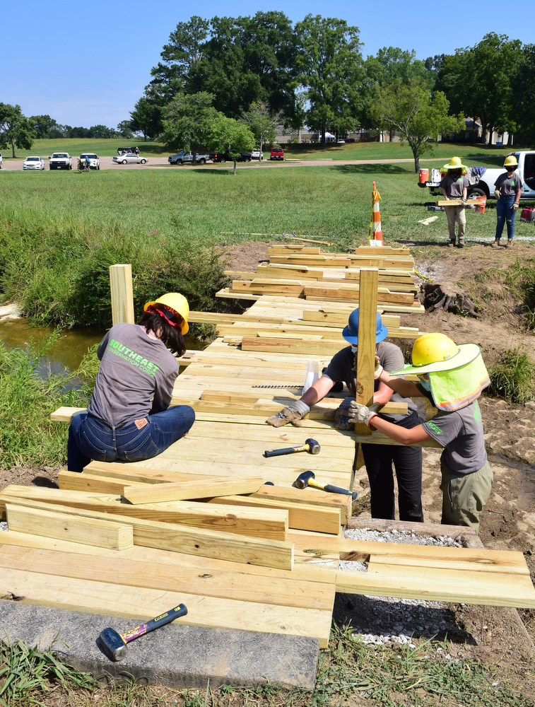 Staff Photo by Robin Rudd / A Southeast Conservation Corps team lays planks for a footbridge they're building across a stream in McDonald Field, just south of the Chickamauga and Chattanooga National Military Park's Visitor Center.