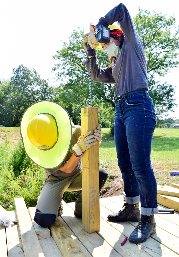 Staff Photo by Robin Rudd / From left, Southeast Conservation Corps' Gracie Fogo holds a post steady while team member Autumn Riehl drills a hole in it. The two are part of a crew building a footbridge across a stream near the Visitors Center at Chickamauga and Chattanooga National Military Park.