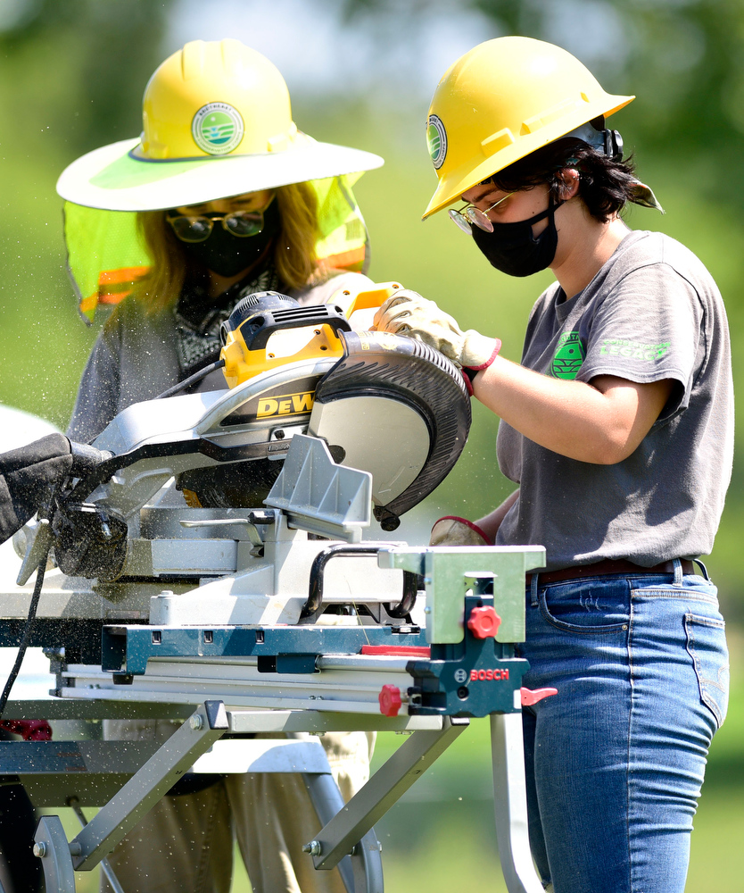 Staff Photo by Robin Rudd / From left, Southeast Conservation Corps team members Juliana Williams and Ruth Beeland cut lumber for the new footbridge being built across a stream in McDonald Field just south of the Visitors Center at Chickamauga and Chattanooga National Military Park.