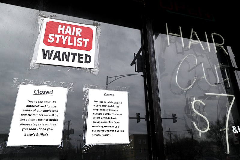 FILE - In this April 30 ,2020 file photo, a barber shop shows closed and hiring sign during the COVID-19 in Chicago.  On Thursday, Aug. 27, just over 1 million Americans applied for unemployment benefits last week, a sign that the coronavirus outbreak continues to threaten jobs even as the housing market, auto sales and other segments of the economy rebound from a springtime collapse. (AP Photo/Nam Y. Huh, File)