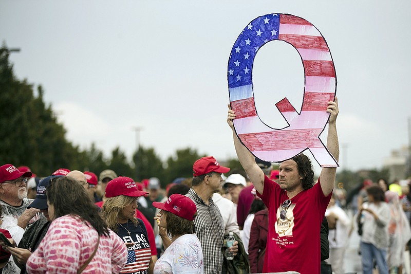 Photo by Matt Rourke of The Associated Press / In this Aug. 2, 2018, file photo, a protester holds a Q sign while waiting in line with others to enter a campaign rally with President Donald Trump in Wilkes-Barre, Pennsylvania.