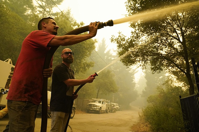 In this Aug. 20, 2020, file photo, civilian volunteers Brian Alvarez, left, and Nate Bramwell fight the CZU Lightning Complex Fire in Bonny Doon, Calif. With California fire crews strapped for resources as hundreds of lightning-sparked fires broke out in one night, crews of organized residents have worked to put out spot fires themselves in a massive complex of blazes along the central coast, banding together to sneak behind evacuation lines and keep properties safe. (AP Photo/Marcio Jose Sanchez, File)