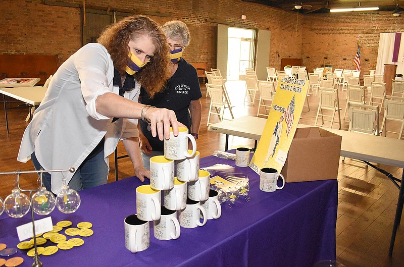 Staff Photo by Matt Hamilton / City recorder Jeannie Anderson sets out mugs featuring a mural celebrating suffrage for women as Niota mayor Lois Preece, back, looks on as they prepare for a celebration of Harry T. Burn on Friday in the Niota Depot. In 1920, Harry T. Burn cast the deciding vote which led to women's suffrage in the United States.