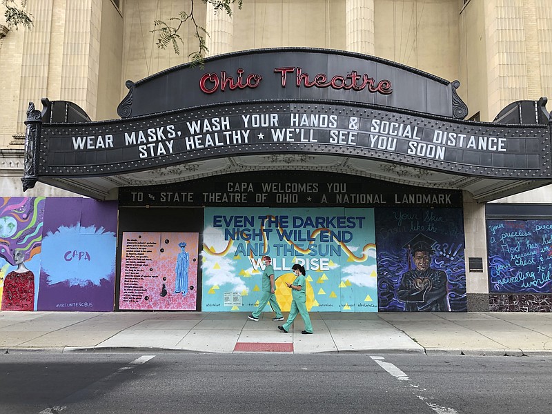 Workers in scrubs and masks walk past the Ohio Theatre in Columbus, Ohio, Wednesday, Aug. 26, 2020, amid the coronavirus pandemic. (AP Photo/Julie Carr Smyth)