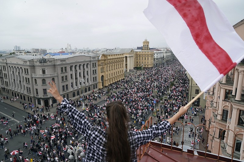 FILE - In this Sunday, Aug. 3, 2020 file photo, a woman waves an old Belarusian national flag standing on the roof as Belarusian opposition supporters march to Independence Square in Minsk, Belarus. The Belarus government has cracked down hard on the news media, deporting some foreign journalists reporting in the country and revoking the accreditation of many Belarusian journalists. Two Moscow-based Associated Press journalists covering the recent protests in Belarus were deported to Russia on Saturday, Aug. 29, 2020. In addition, the AP's Belarusian staff were told by the government that their press credentials had been revoked. The AP said it decries the moves as a "blatant attack on press freedom." Protests in Belarus began after the Aug. 9 election that officials said gave President Alexander Lukashenko a sixth term. Protesters say the election results were rigged and are demanding that Lukashenko resign after 26 years in power. (AP Photo/Evgeniy Maloletka, File)


