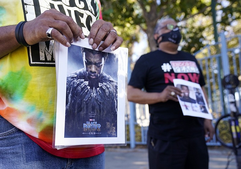A portrait of the late actor Chadwick Boseman as the character T'Challa in the 2018 film "Black Panther" is held by a participant in a news conference celebrating his life, Saturday, Aug. 29. 2020, in Los Angeles. Boseman died Friday at 43 after a four-year fight with colon cancer. (AP Photo/Chris Pizzello)