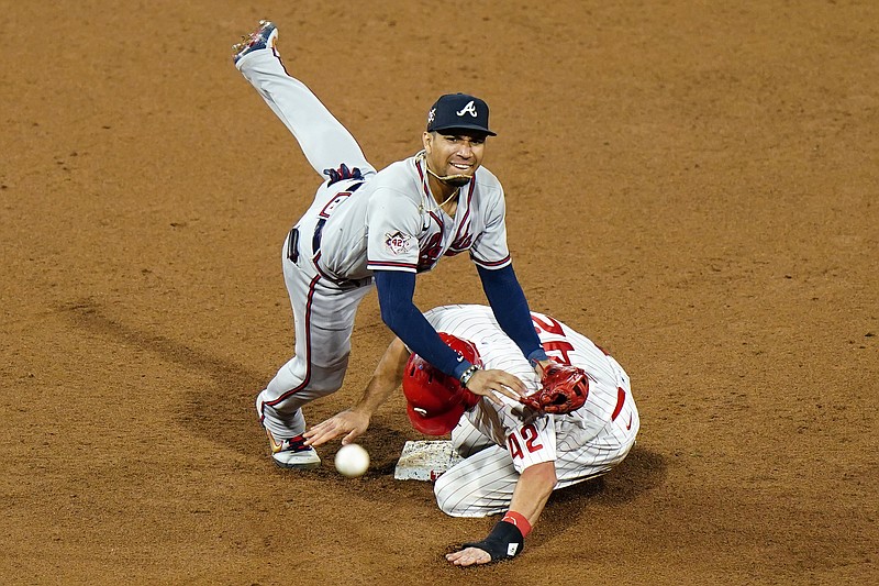 AP photo by Matt Slocum / Atlanta Braves second baseman Johan Camargo, left, leaps over the Philadelphia Phillies' J.T. Realmuto after forcing him out on a double play hit into by Jean Segura during the ninth inning of Sunday night's game in Philadelphia.