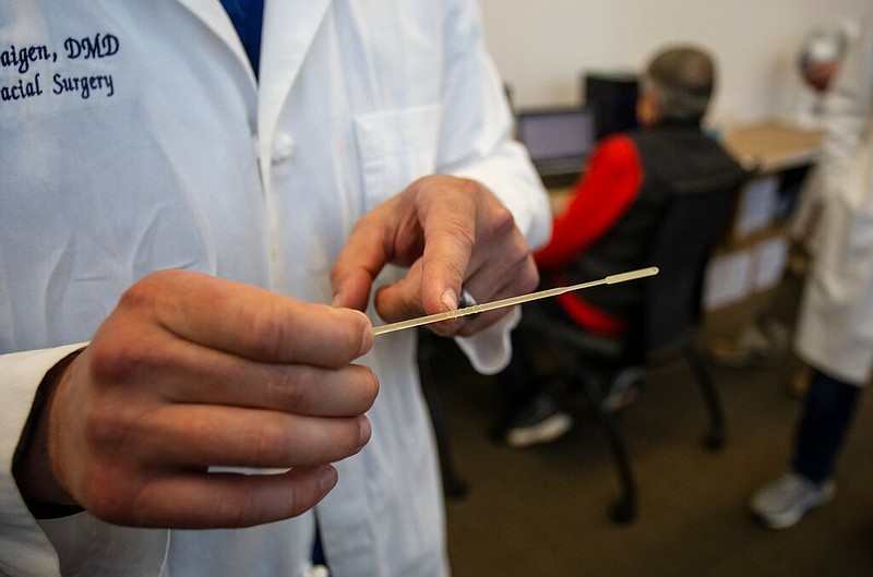 Alexander Faigen, of Augusta University's Dental College of Georgia, shows how far a nasal swab must be inserted in Augusta, Ga. (AP Photo/Ron Harris)