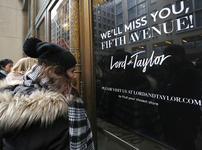 FILE - In this Jan. 2, 2019 file photo, women peer in the front door of Lord & Taylor's flagship Fifth Avenue store which closed for good, in New York. A slew of once-beloved brands from Lord & Taylor to Ann Taylor have filed for Chapter 11 since the pandemic. Many shoppers will see these iconic labels vanish or become mere shadows of themselves as they drastically shrink their businesses or get acquired. But while loyal customers bemoan their loss, the brands themselves have been clearly losing favor for year. (AP Photo/Kathy Willens, File)